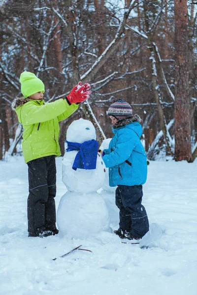 Веселые, счастливые дети, играющие со снеговиком — стоковое фото