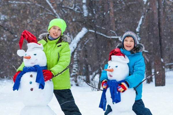 Diversão, crianças felizes brincando com boneco de neve — Fotografia de Stock