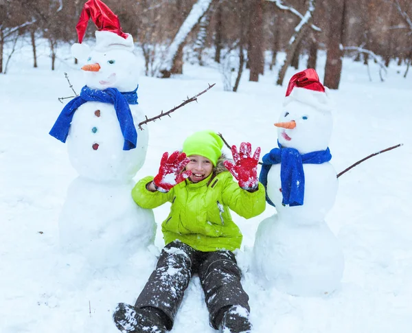 Zábava, šťastné dítě hraje s sněhulák v zimě parku — Stock fotografie