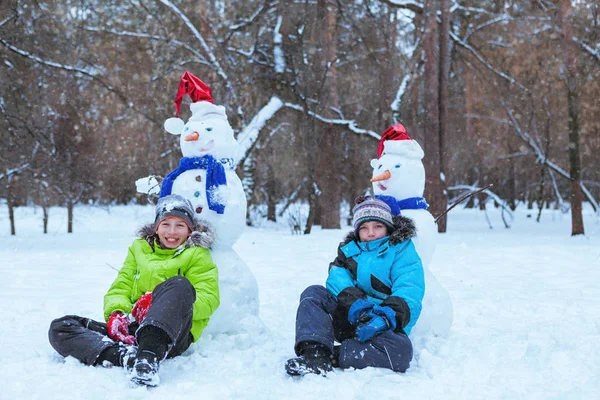 Веселые, счастливые дети, играющие со снеговиком — стоковое фото