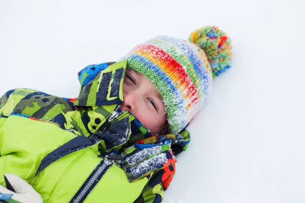 Vrolijke happy jongen liggen op sneeuw, — Stockfoto