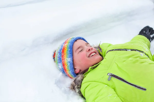 Glad lycklig pojke lögn på snö, — Stockfoto