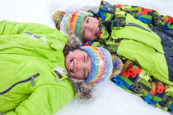 Vrolijke happy jongens liggen op sneeuw, — Stockfoto