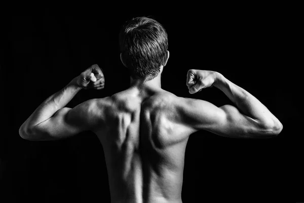 Portrait of young and fit teen model posing his muscles in studio