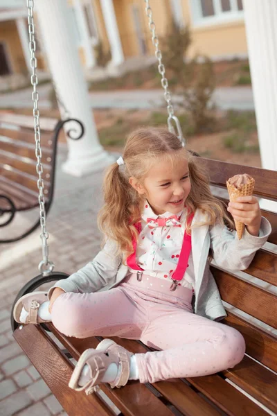 Dondurma yiyen mutlu kız, evin avlusunda ahşap bir salıncakta oturuyor. Açık hava, yaz.. — Stok fotoğraf