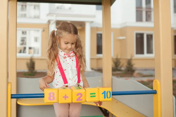 Csinos kislány megtanul számolni, óvodás az óvodában a játszótéren. — Stock Fotó
