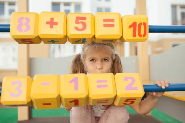 Mooi klein meisje leren tellen, kleuter op de kleuterschool op de speelplaats — Stockfoto