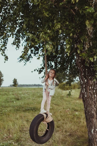 Happy girl swinging on a wheel, walk in nature — Stock Photo, Image