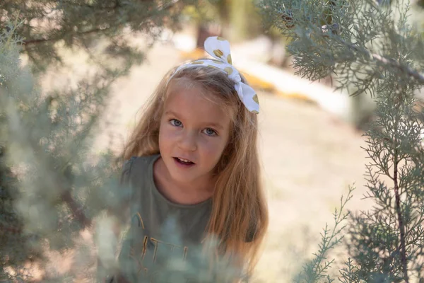 Emotionales Porträt eines positiven und fröhlichen kleinen Mädchens mit langen Haaren, das im Park spazieren geht. glückliche Kindheit. Sommerzeit. Sommerurlaub in der Natur — Stockfoto