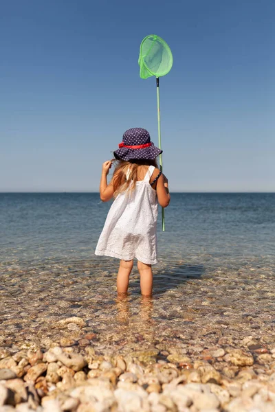 Ritratto di graziosa ragazza allegra e felice che indossa un cappello, all'aperto. Ragazza in piedi sulla riva del mare . — Foto Stock