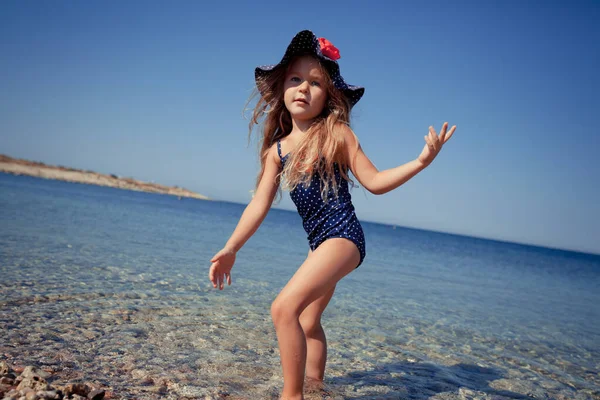 Retrato de linda chica alegre, feliz con sombrero y gafas de sol, al aire libre. Chica sentada en la orilla del mar . — Foto de Stock