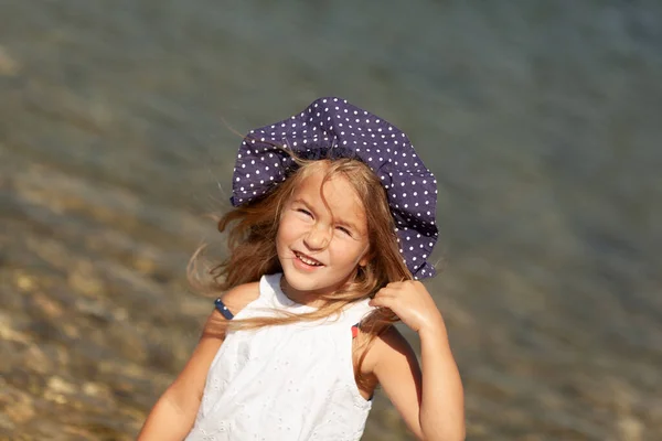 Portret uroczej wesołej, szczęśliwej dziewczyny w kapeluszu, na świeżym powietrzu. Dziewczyna stojąca na brzegu morza. — Zdjęcie stockowe