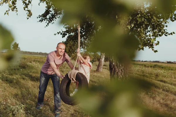 Mutlu baba ve kız bir tekerlekte sallanıyor, doğada yürüyor, yaz mevsiminde, — Stok fotoğraf