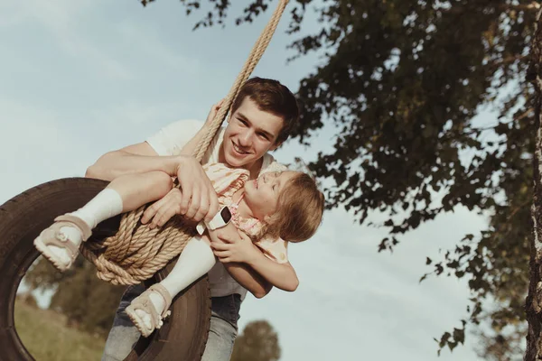 Big brother plays with little sister, shakes her on the wheel — Stock Photo, Image