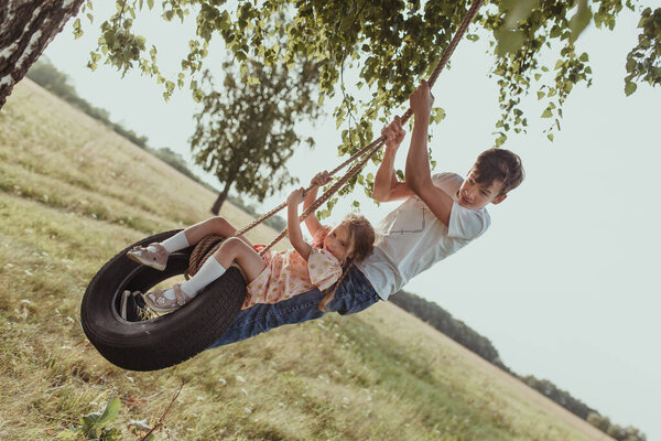 Старший брат играет с младшей сестрой, трясет ее на руле
