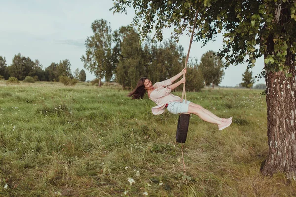 Menina feliz balançando em uma roda, andar na natureza — Fotografia de Stock