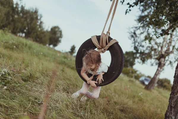 Menina feliz balançando em uma roda, andar na natureza — Fotografia de Stock