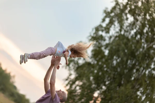 Father throws a happy daughter high in the sky, sunset, summer — Stock Photo, Image