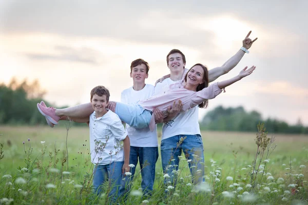 Ritratto di una grande famiglia felice su uno sfondo di natura estiva, una passeggiata nel campo, Tre figli tengono una mamma felice tra le braccia — Foto Stock