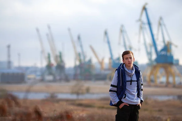 Portrét pohledného, vážně brutálního chlapa. Teenager stojí na pozadí jeřábů — Stock fotografie