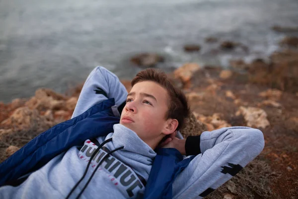 Egy jóképű, komoly, brutális fickó portréja. Egy tinédzser fekszik a tengerparton.. — Stock Fotó