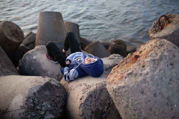 一个英俊而严肃的野蛮人的画像。 一个在海边的少年躺在防波堤上. — 图库照片