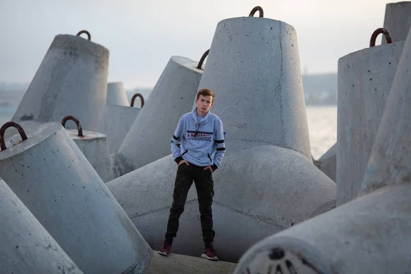 Portrét pohledného, vážně brutálního chlapa. Teenager u moře, stojí na vlnolamu. — Stock fotografie