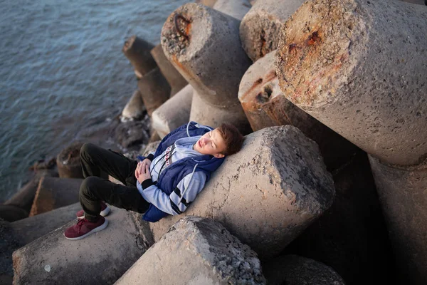 Portrét pohledného, vážně brutálního chlapa. Mladík u moře, leží na vlnolamech. — Stock fotografie