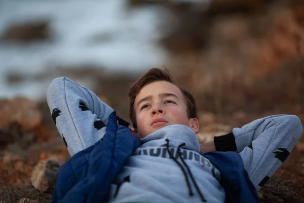 Porträt eines gutaussehenden, brutalen Typen. ein Teenager am Meer, liegt an der Küste. — Stockfoto