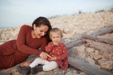 Küçük bir kız ve anne deniz kenarında yürür, oynarlar.