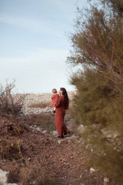 Küçük bir kız ve anne deniz kenarında yürür, oynarlar ve sarılırlar.