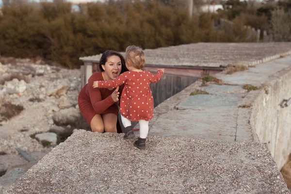 En liten flicka och mamma går nära havet, de leker och kramas — Stockfoto