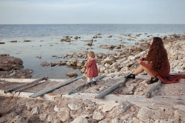 一个小女孩和妈妈在海边散步，他们在一起玩耍 — 图库照片