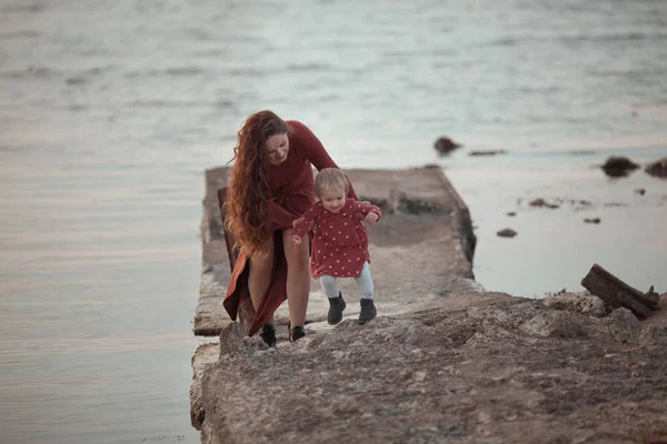一个小女孩和妈妈在海边散步，他们玩耍着，拥抱着 — 图库照片