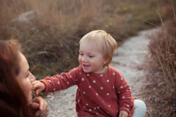 Ein kleines Mädchen und eine Mutter gehen, sie spielen und umarmen sich, im Freien — Stockfoto