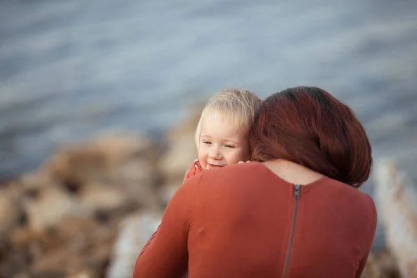 Porträt einer glücklichen Mutter und Tochter, Mutter umarmt ein kleines Mädchen auf einem Meeresgrund — Stockfoto