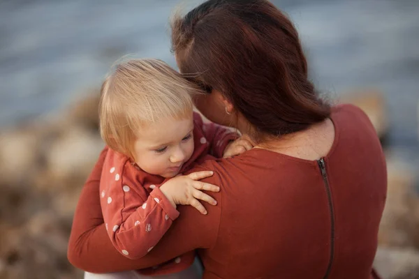 Porträt einer glücklichen Mutter und Tochter, Mutter umarmt ein kleines Mädchen auf einem Meeresgrund — Stockfoto