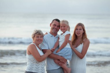 Portrait of happy family. They hug on the background of the sea.