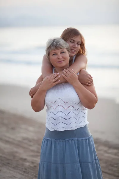 Retrato de uma mãe feliz e filha adulta. Abraçam-se no fundo do mar . — Fotografia de Stock