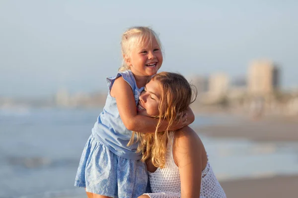 Portret van gelukkige zussen. Ze knuffelen op de achtergrond van de zee. — Stockfoto