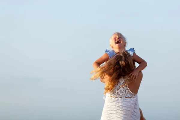 Portrait of happy sisters. They hug on the background of the sea. — Stok fotoğraf