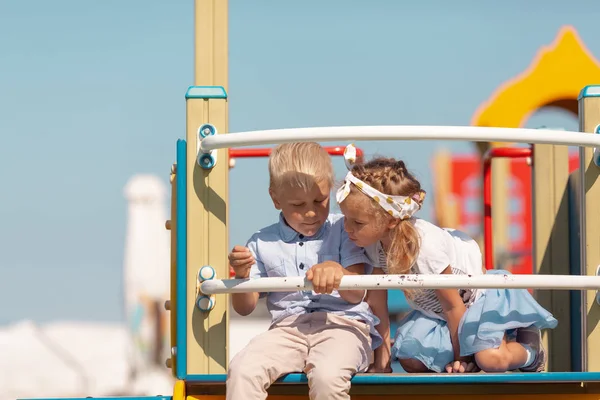 Chica y niño juegan en el patio de recreo, amigos se comunican en el jardín de infantes —  Fotos de Stock