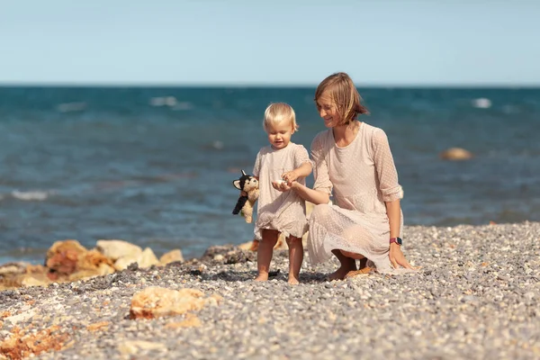 Красивая счастливая мама и маленькая дочь на прогулке у моря — стоковое фото