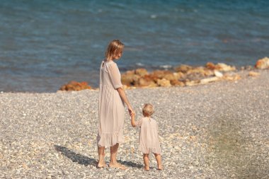 Pretty happy mom and little daughter on a walk near the sea