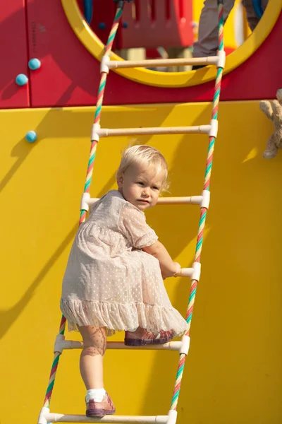 Menina feliz joga no playground, ao ar livre, verão — Fotografia de Stock