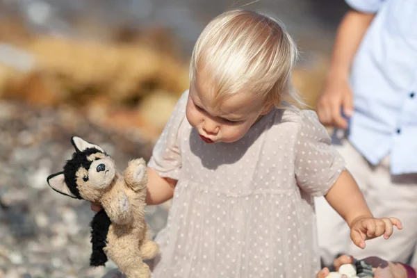 Portret van een mooi klein meisje op de achtergrond van de zee, de baby loopt op de kust — Stockfoto