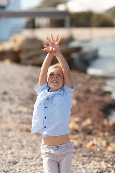 The boy throws stones up on the seashore — Stok fotoğraf