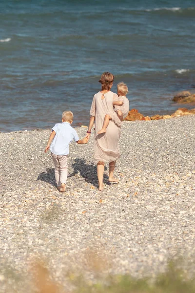 Jolie maman heureuse et petits enfants en promenade près de la mer — Photo
