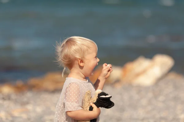 Portrait of a pretty little girl on the background of the sea, the baby walks on the shore — Stok fotoğraf