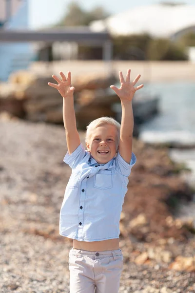 The boy throws stones up on the seashore — Stock Photo, Image